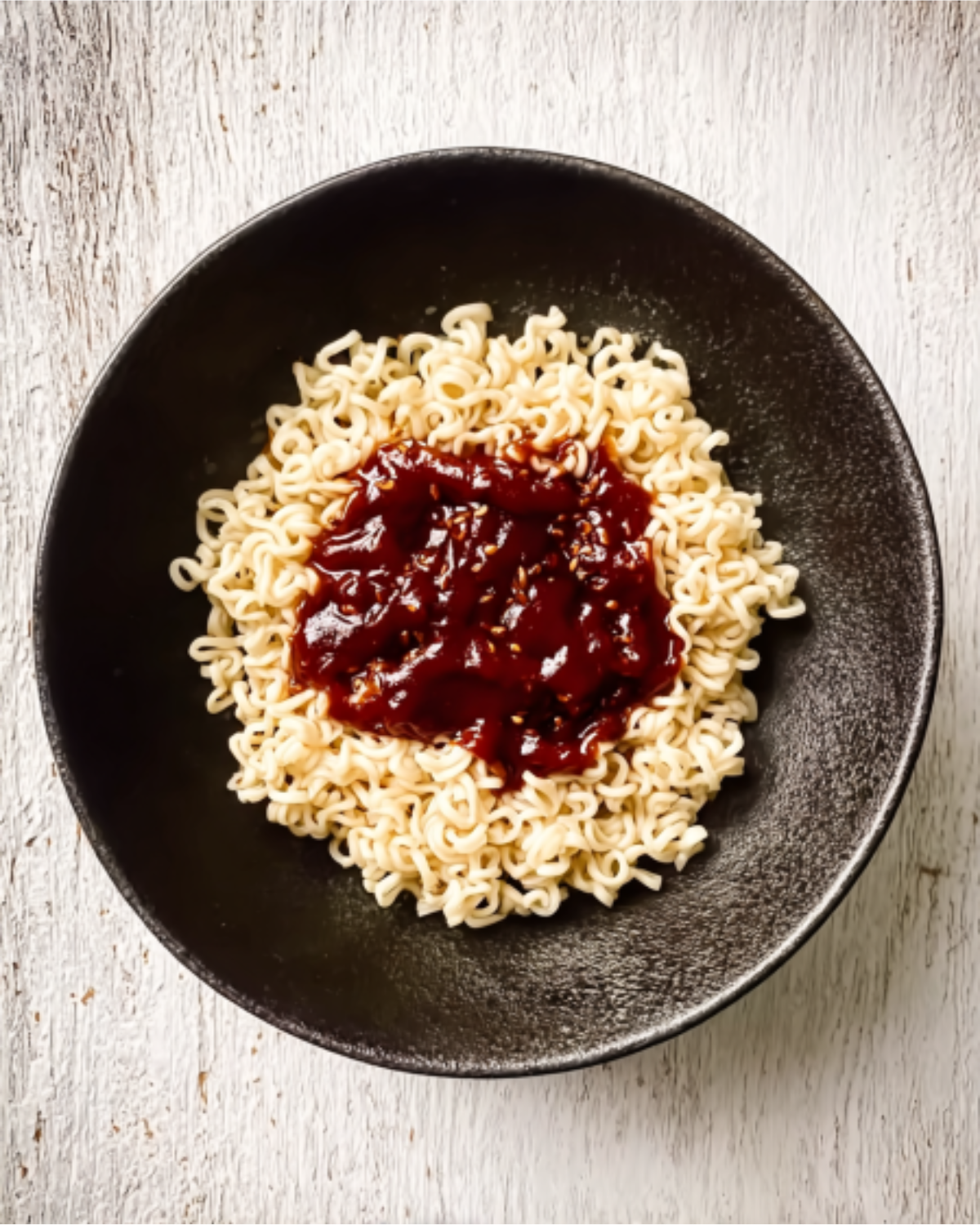 buldak-ramen-recipe-noodles-with-spicy-sauce Bowl of cooked noodles topped with spicy red sauce for buldak ramen recipe