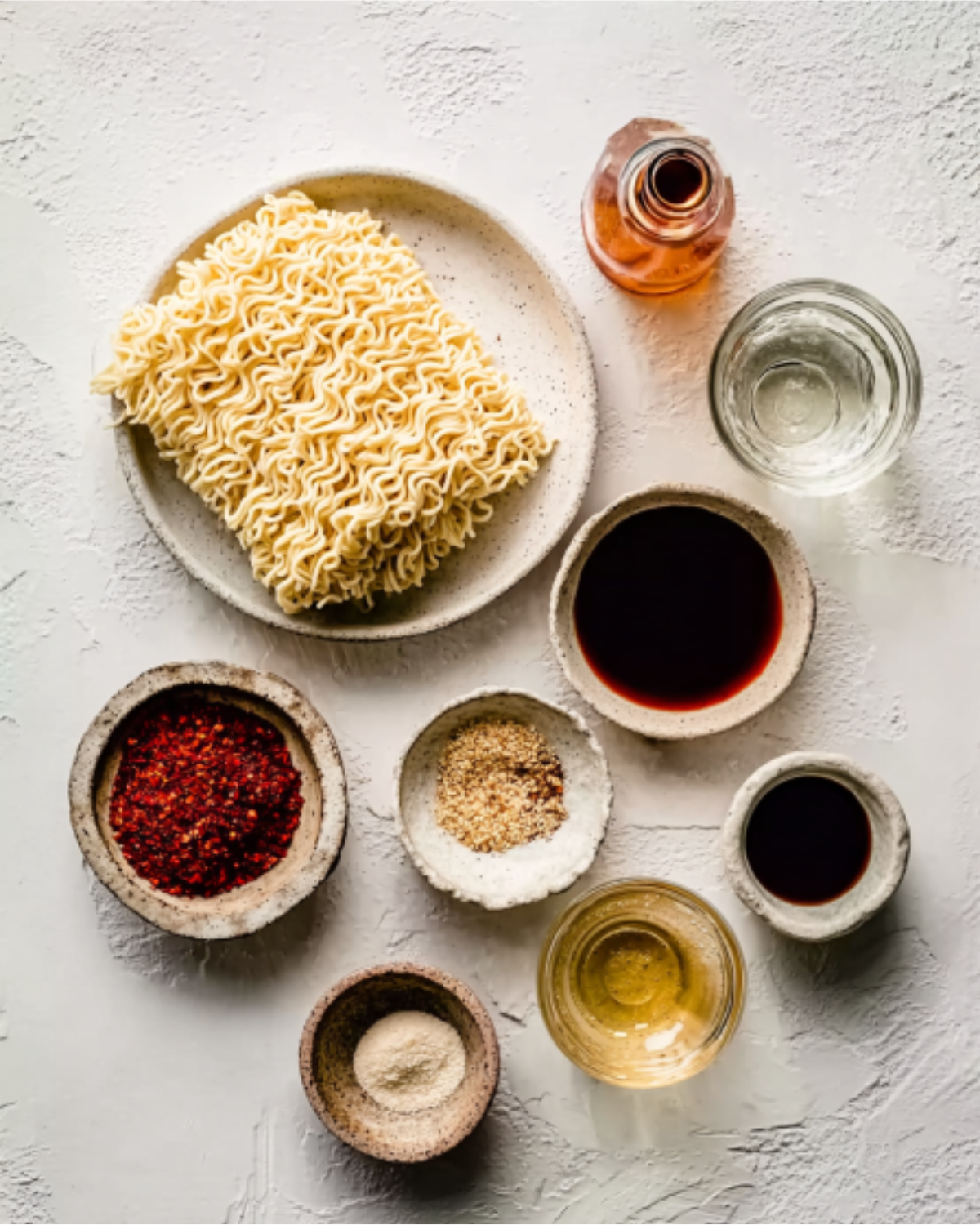 buldak-ramen-recipe-ingredients-flatlay Flatlay of ingredients including instant noodles, chili flakes, soy sauce, and sesame seeds for buldak ramen recipe