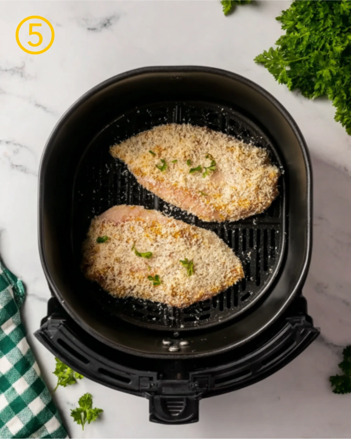 Step five of Air Fryer Parmesan Crusted Chicken showing breaded chicken breasts placed in an air fryer basket