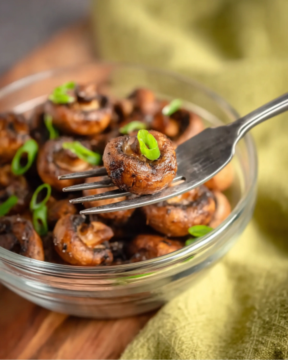 air-fryer-mushrooms-closeup-serving Close-up of a fork holding a perfectly roasted Air Fryer Mushroom garnished with green onion over a serving bowl