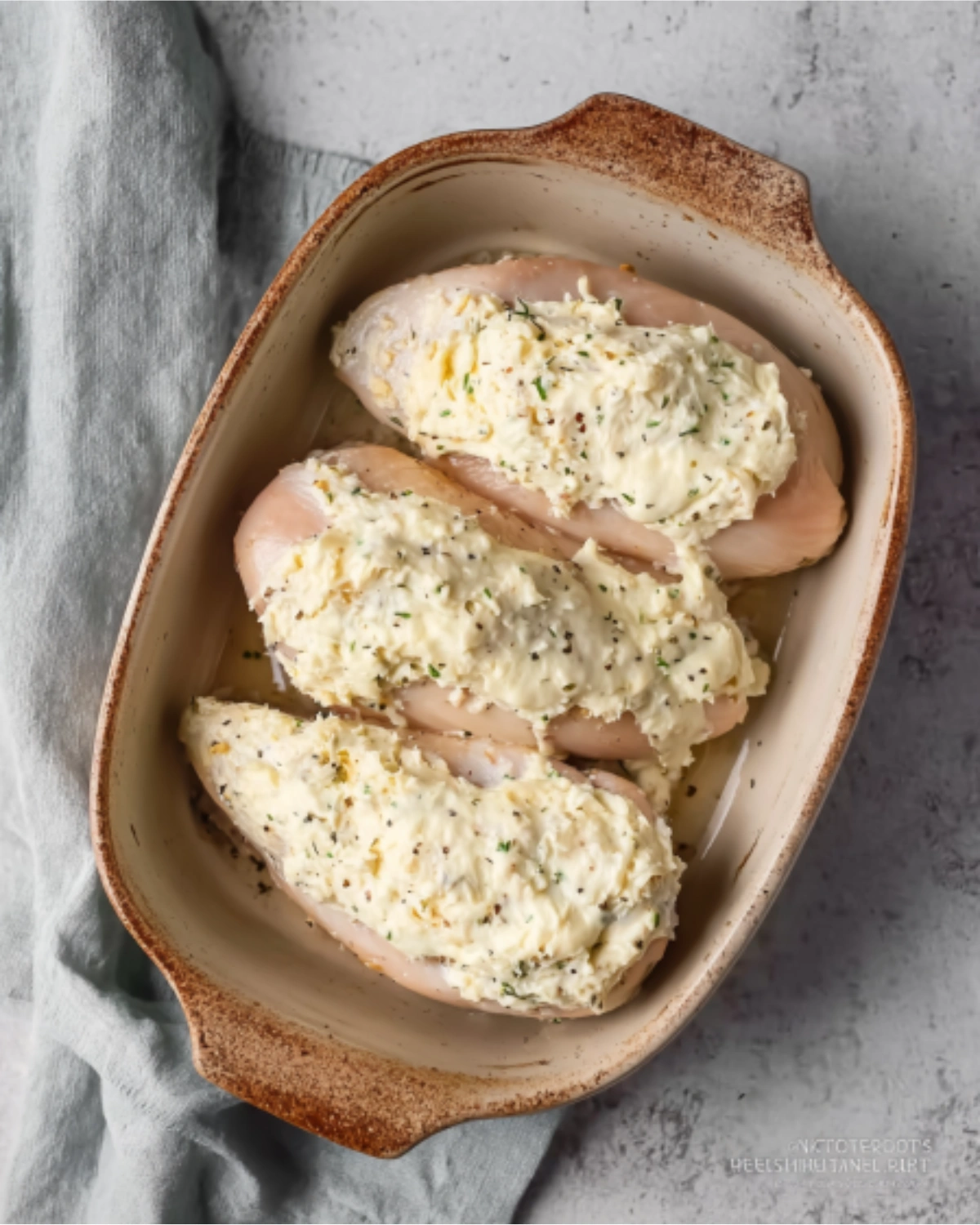 melt-in-your-mouth-chicken-breast-recipe Melt In Your Mouth Chicken Breast Recipe prepared in a ceramic baking dish, topped with creamy seasoned mixture