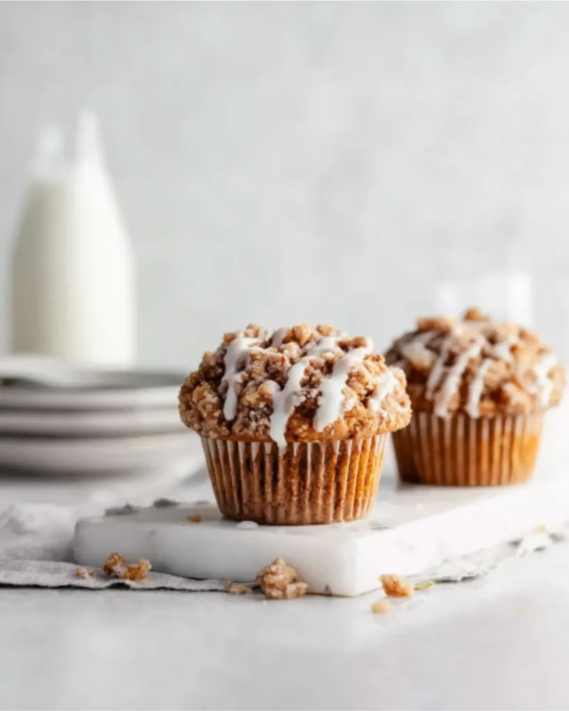 Freshly baked pumpkin streusel muffins with crumble topping and icing drizzle