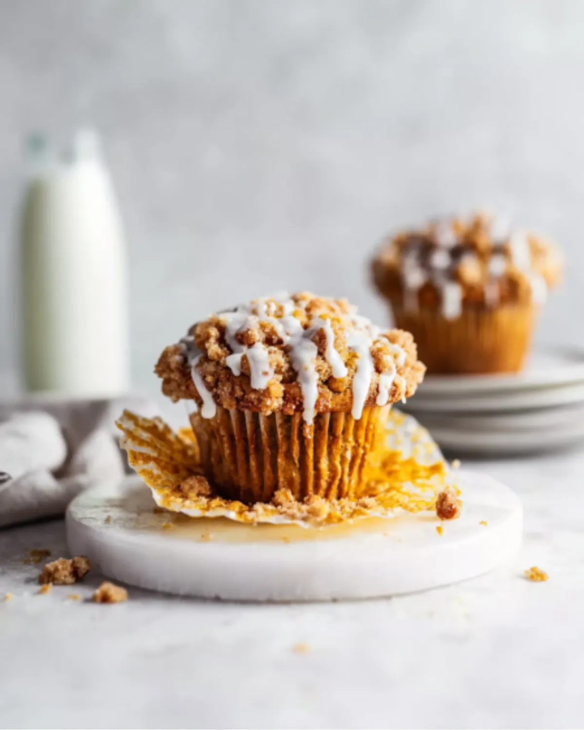 Moist pumpkin streusel muffin with crumb topping and icing, partially unwrapped for a close-up view