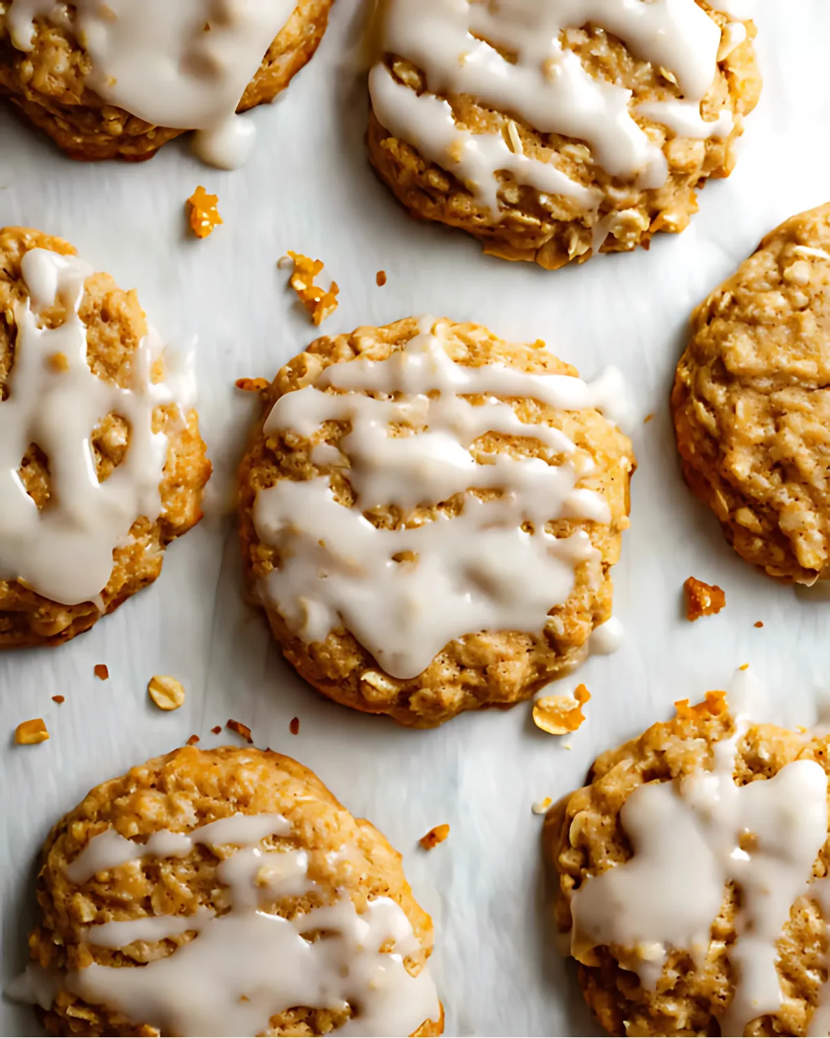 pumpkin-oatmeal-cookies-drizzled-icing-baking-sheet Pumpkin oatmeal cookies on parchment paper with vanilla icing drizzle