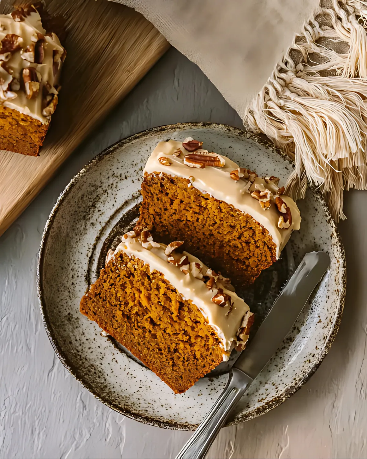 Two slices of 2 ingredient pumpkin bread with glaze and pecans served on a rustic ceramic plate.
