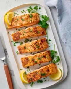 Air Fryer Salmon Recipe served with lemon wedges and fresh herbs on a white platter