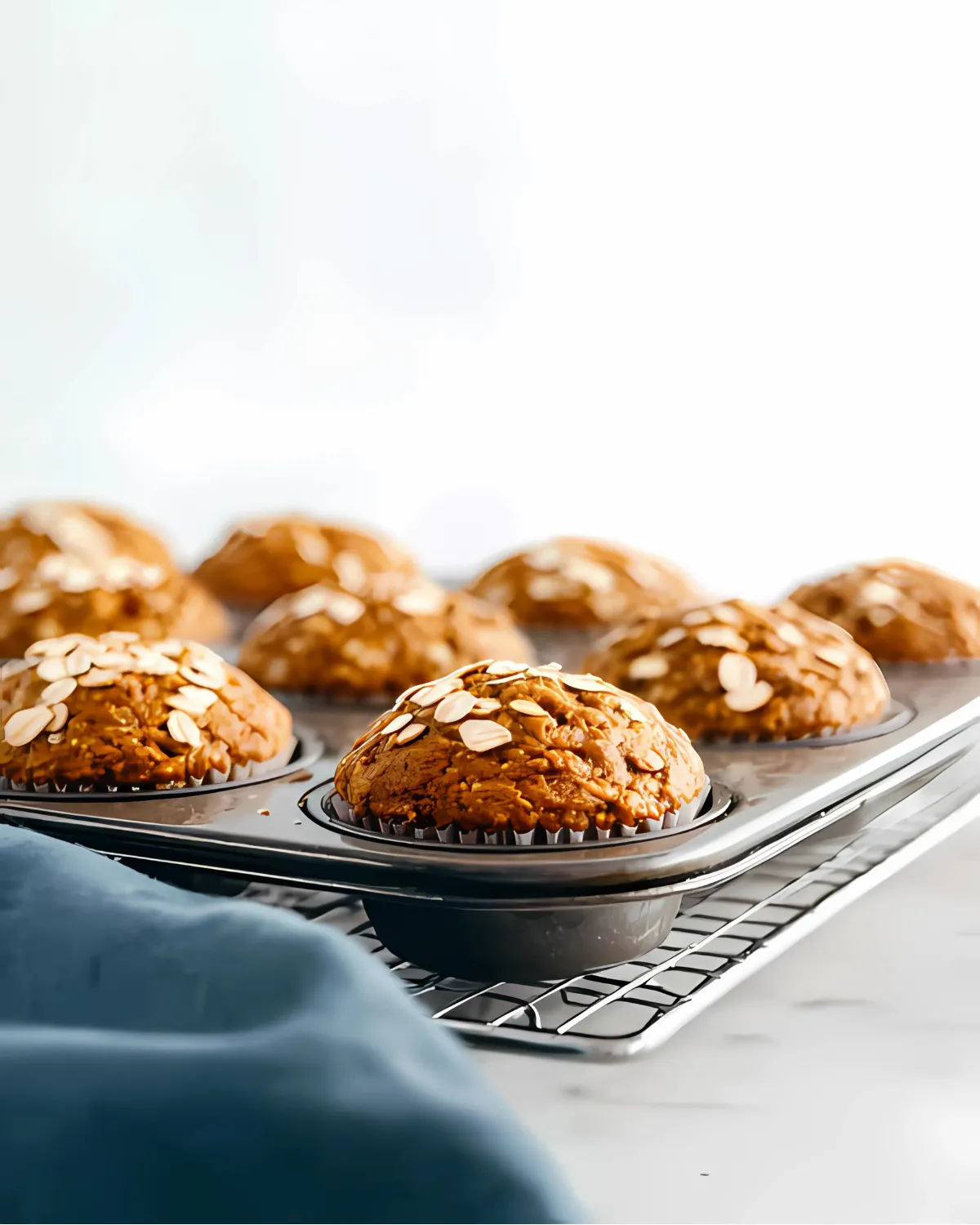 Freshly baked pumpkin oatmeal muffins topped with oats in a muffin tray