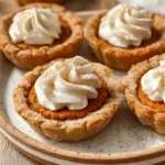 Close-up of Pumpkin Pie Cookies with golden crust and whipped cream topping on a speckled plate