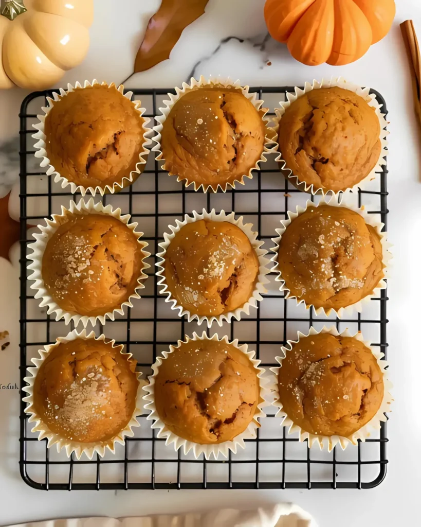 Top view of nine freshly baked Kodiak Pumpkin Muffins on a cooling rack with fall decor.