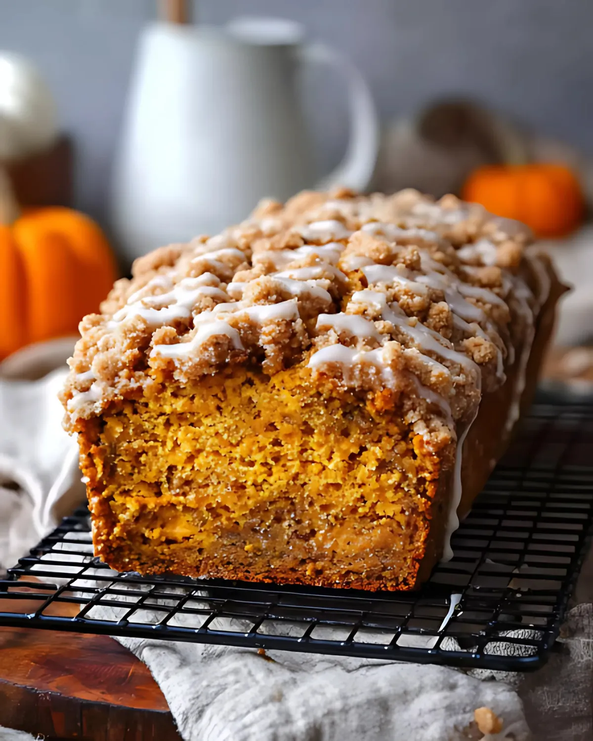 pumpkin-streusel-bread-moist-loaf Moist and tender Pumpkin Streusel Bread loaf with crumb topping and vanilla glaze, displayed on a cooling rack.