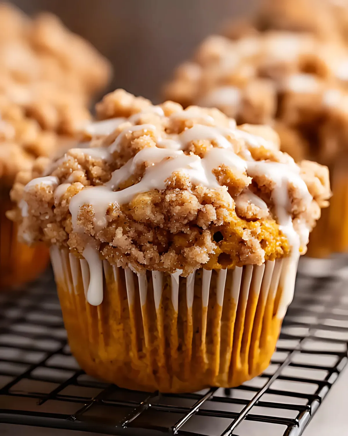 pumpkin-crumb-muffins-with-vanilla-glaze Close-up of freshly baked Pumpkin Crumb Muffins topped with vanilla glaze on a cooling rack