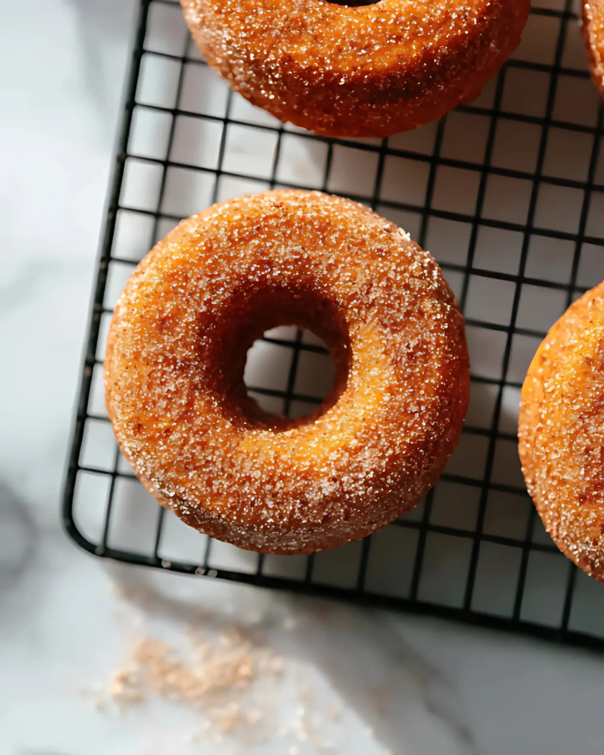 pumpkin-spice-donuts-baked-cooling-rack Pumpkin spice donuts cooling on a wire rack, dusted with cinnamon sugar.