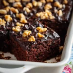 Close-up of moist black bean Halloween brownies in a white baking dish, topped with chocolate chips and walnuts