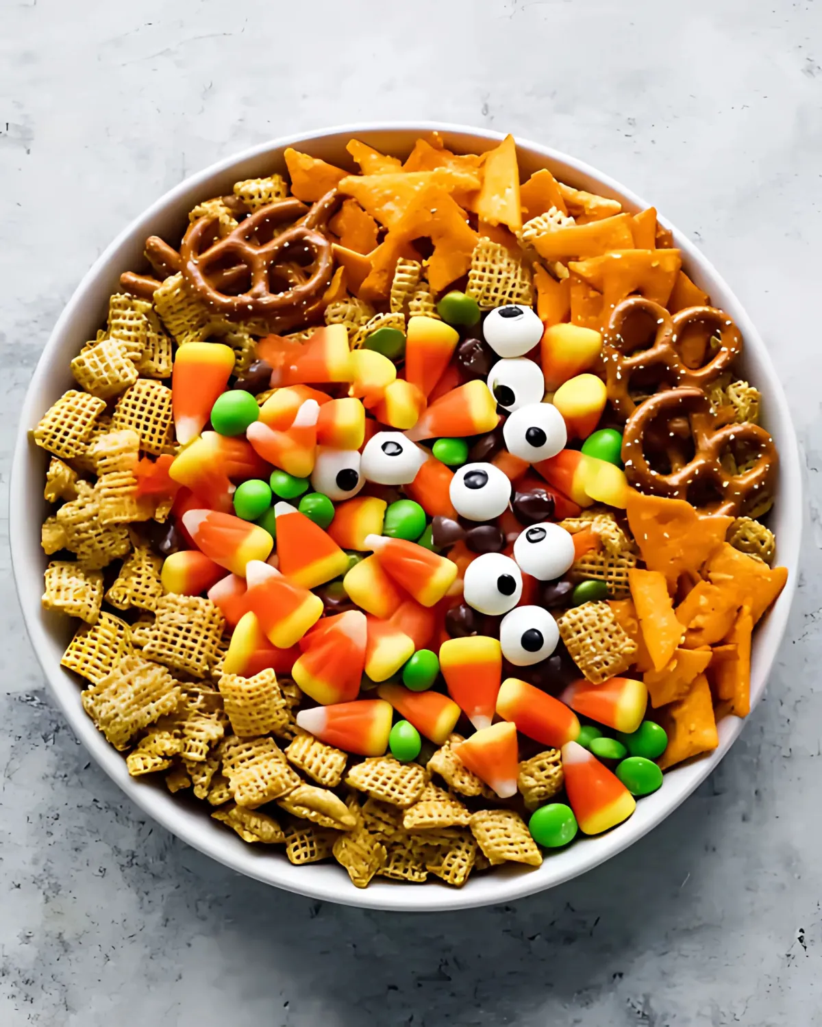 Top view of Halloween Harvest Snack Mix featuring candy corn, pretzels, Chex cereal, green candies, and candy eyeballs