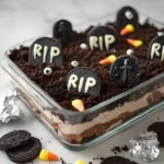 Graveyard Chocolate Cake layered with chocolate pudding, crushed Oreos, and candy decorations for a spooky Halloween dessert