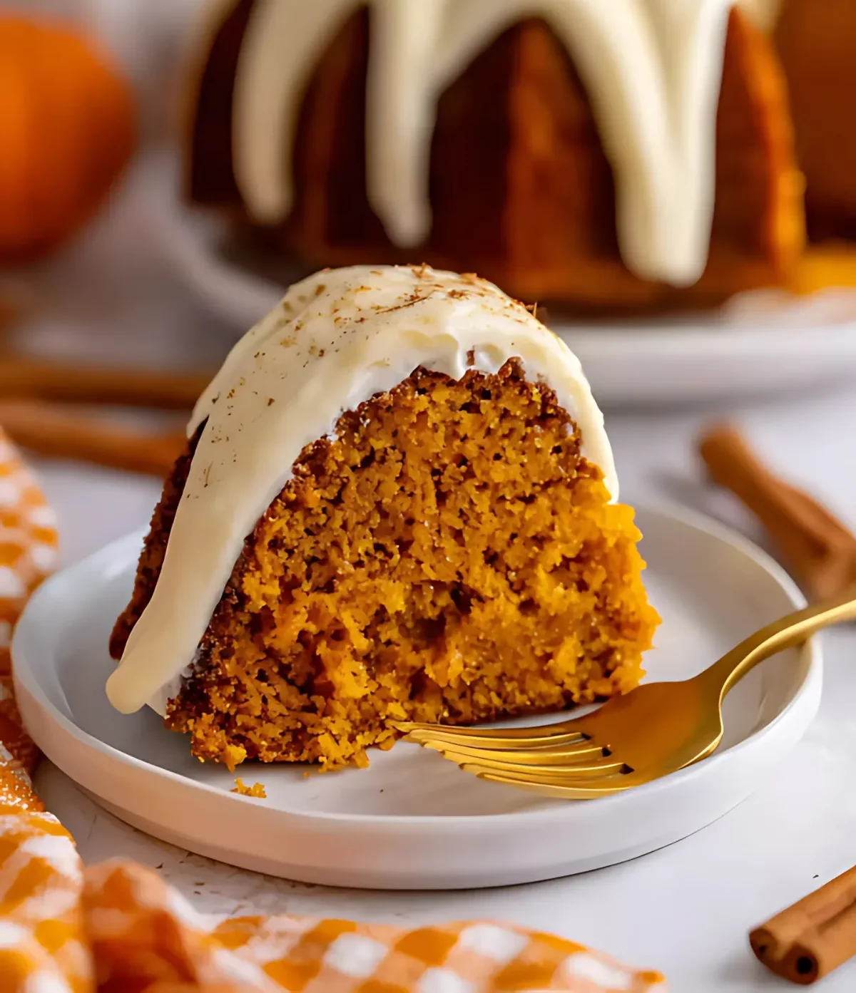 Close-up of a moist Pumpkin Spice Bundt Cake slice topped with vanilla glaze on a white plate