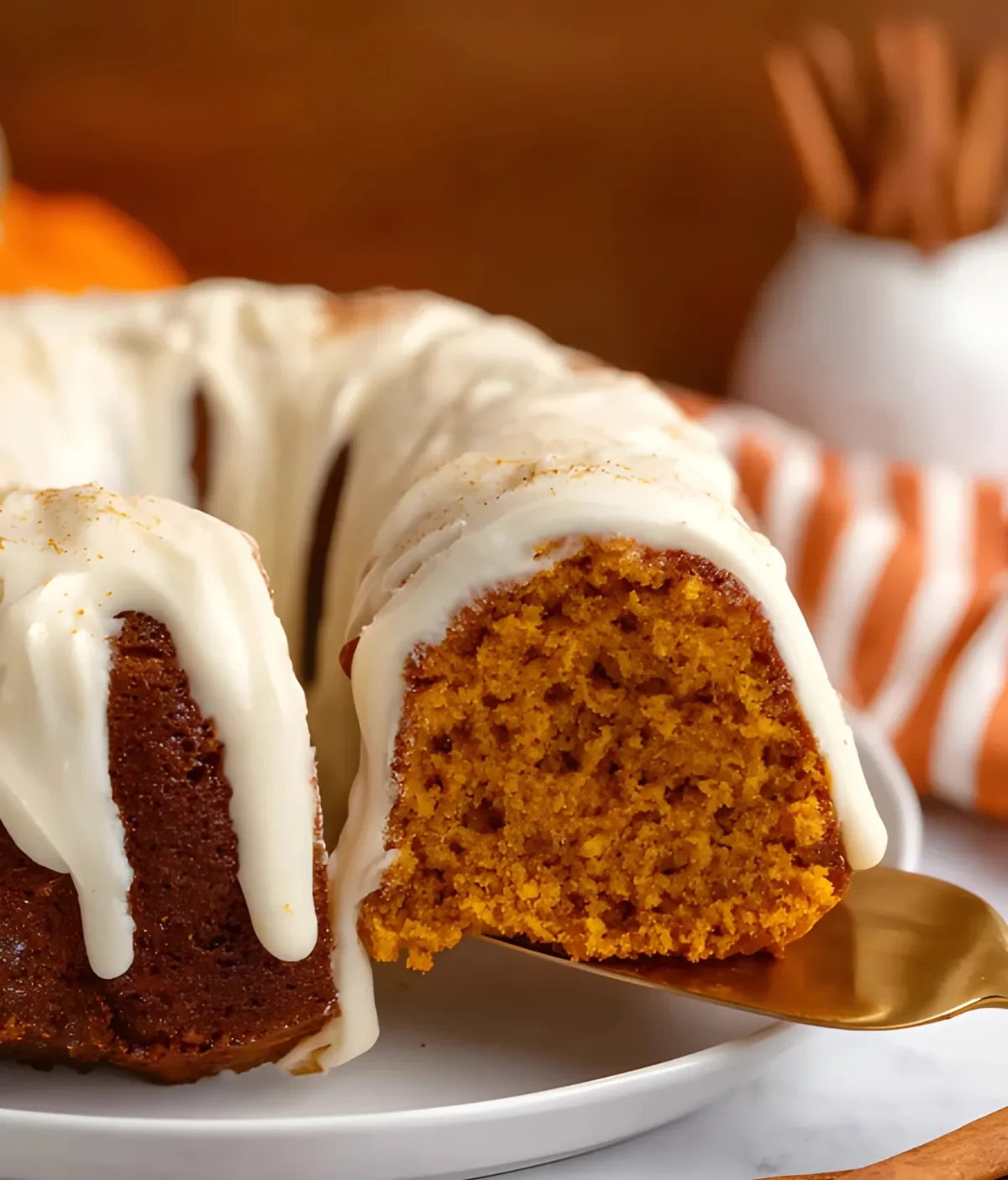 Pumpkin Spice Bundt Cake slice being served with creamy vanilla glaze and warm spiced interior