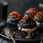Halloween Funfetti Cupcakes with dramatic black swirl frosting and orange sprinkles on a black plate