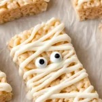 Close-up of Halloween Rice Krispie Treats decorated as mummies with white chocolate drizzle and candy eyes