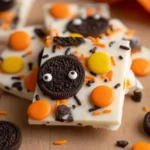 Halloween Oreo Bark topped with candy eyes, orange and yellow chocolates, and festive sprinkles