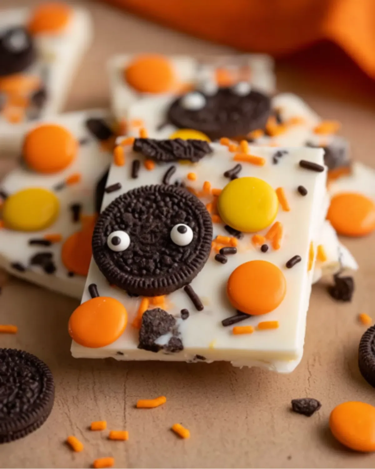Halloween Oreo Bark topped with candy eyes, orange and yellow chocolates, and festive sprinkles