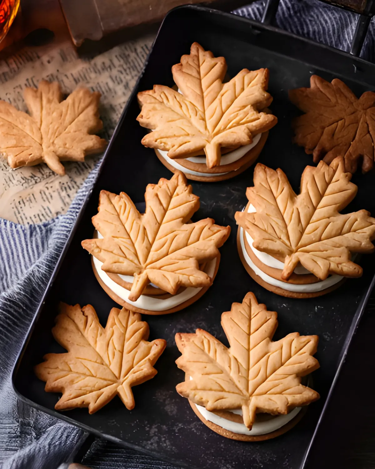 Homemade Fall Leaf Cookies with maple cream filling arranged in a black tray