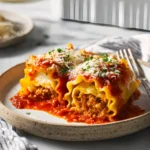 Close-up of Halloween Lasagna Roll-ups topped with marinara sauce and parmesan cheese on a ceramic plate