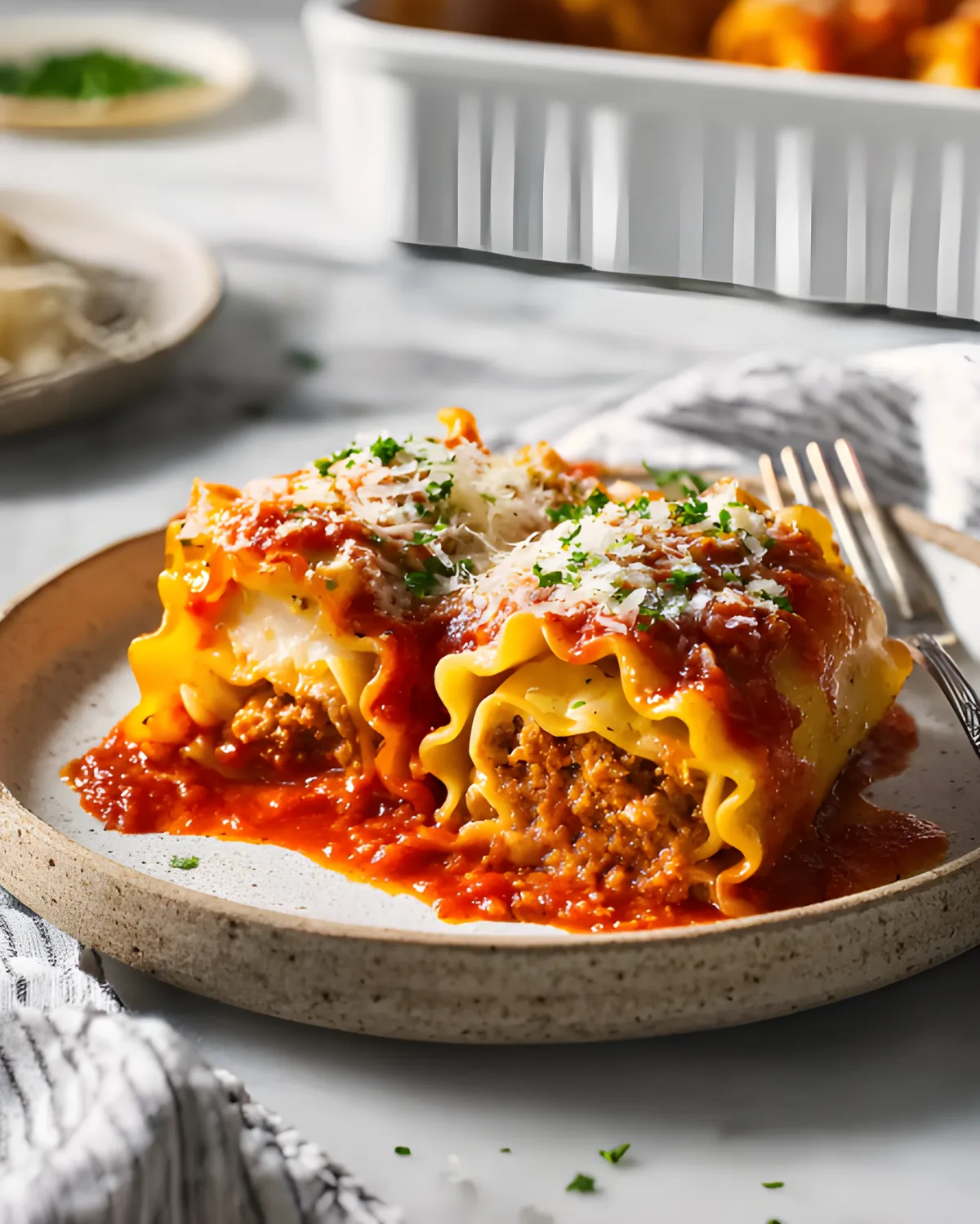 Close-up of Halloween Lasagna Roll-ups topped with marinara sauce and parmesan cheese on a ceramic plate