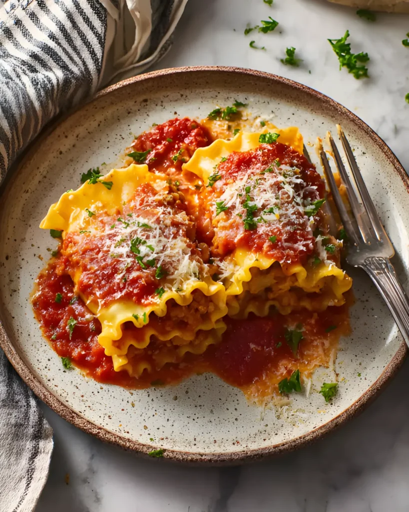 Plate of Halloween Lasagna Roll-ups garnished with fresh parsley and parmesan cheese, served with a fork