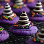 Halloween Witch Hat Cookies cooling on a wire rack, decorated with purple sugar, striped chocolate kisses, and colorful sprinkles