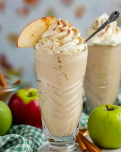 Creamy apple pie milkshake topped with whipped cream, cinnamon, and a fresh apple slice, served in a vintage glass