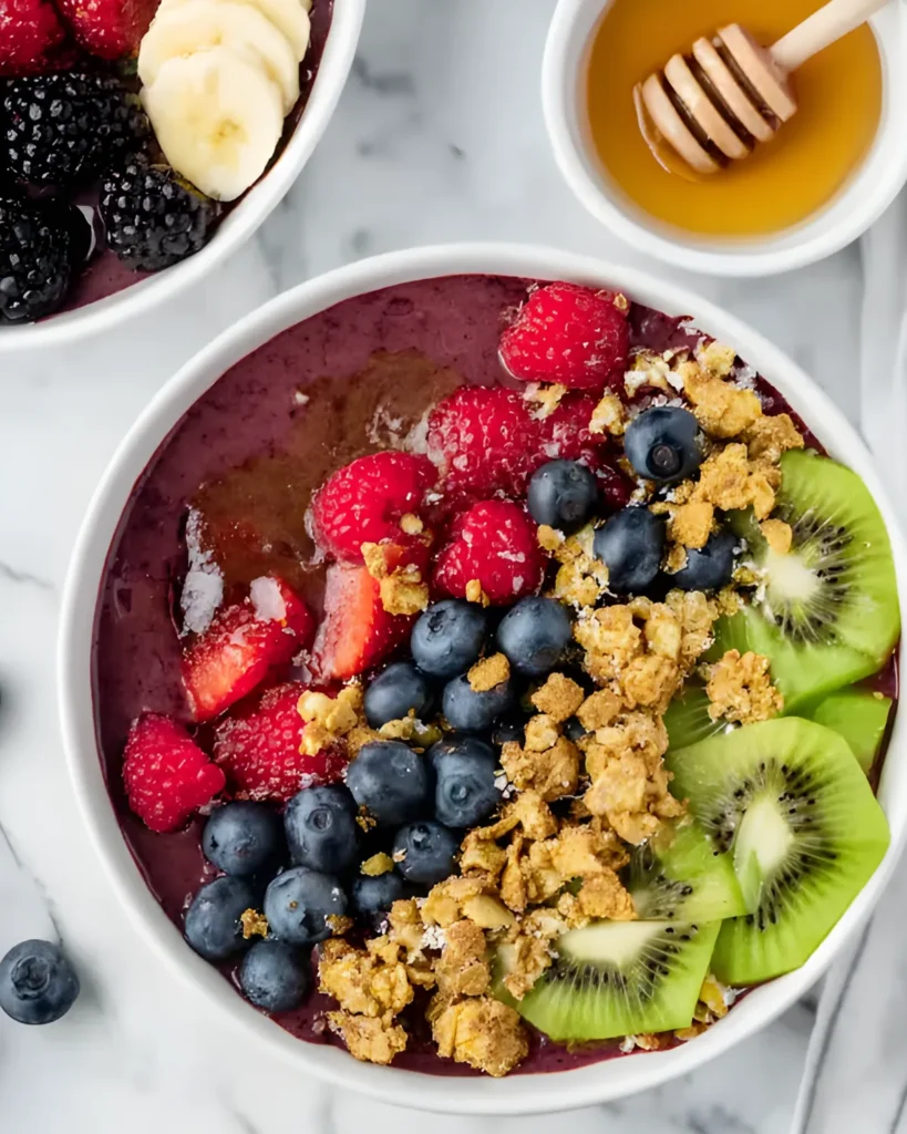 Homemade Acai Smoothie Bowl topped with granola, kiwi, blueberries, raspberries, and drizzled honey