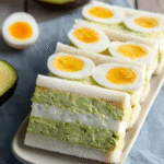 Japanese Style Avocado Egg Salad sandwich slices layered with creamy avocado spread and soft-boiled eggs.