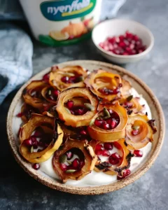 Apple Cinnamon Yogurt Bowl topped with roasted squash rings, pomegranate seeds, and pumpkin seeds in a ceramic bowl