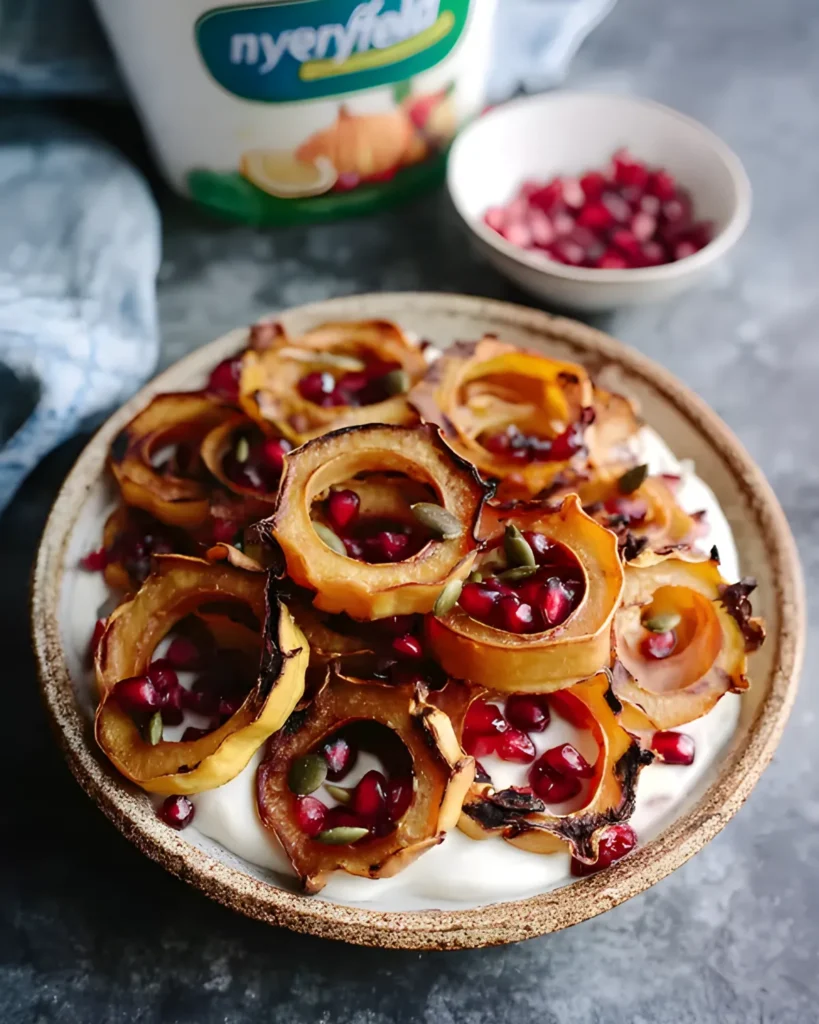 Apple Cinnamon Yogurt Bowl topped with roasted squash rings, pomegranate seeds, and pumpkin seeds in a ceramic bowl