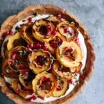 Apple Cinnamon Yogurt Bowl topped with roasted squash rings, pomegranate seeds, and fresh thyme in a rustic wooden bowl