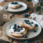 Blueberry Bagel Recipe served with cream cheese and fresh blueberries on a rustic wooden table