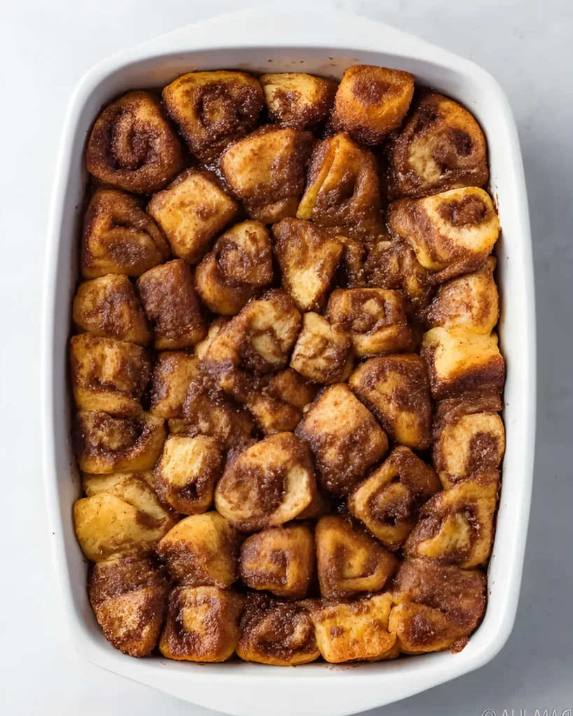 Golden-brown cinnamon roll casserole baked in a white dish without icing