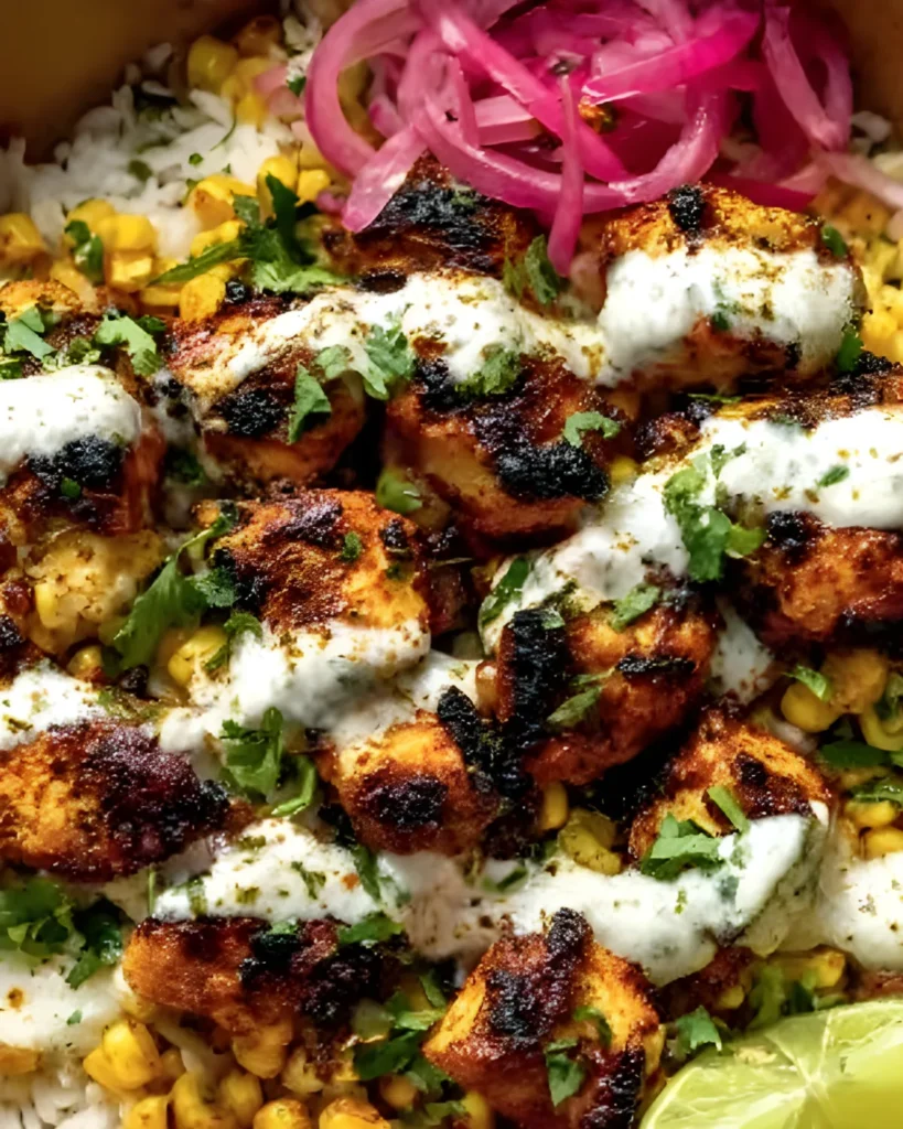 Close-up of Corn Chicken Bowl with grilled chicken, roasted corn, white sauce drizzle, pickled onions, rice, and lime.