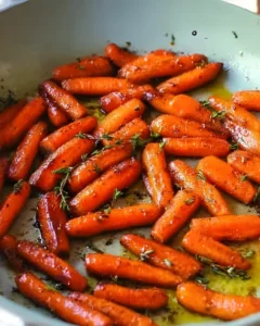 Honey Roasted Carrots caramelized in a skillet with fresh thyme and glossy honey glaze