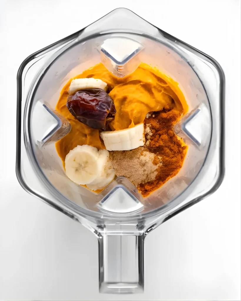 Pumpkin Pie Smoothie Bowl ingredients in a blender with banana, pumpkin puree, date, and spices