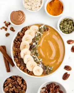Pumpkin Pie Smoothie Bowl topped with banana slices, granola, seeds, and spices