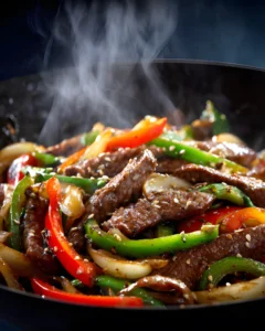 Sizzling Chinese Pepper Steak stir fry with tender beef strips, bell peppers, and onions in a hot skillet