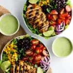 Two bowls of Southwest chicken salad with grilled chicken, black beans, corn, tomatoes, and cilantro dressing