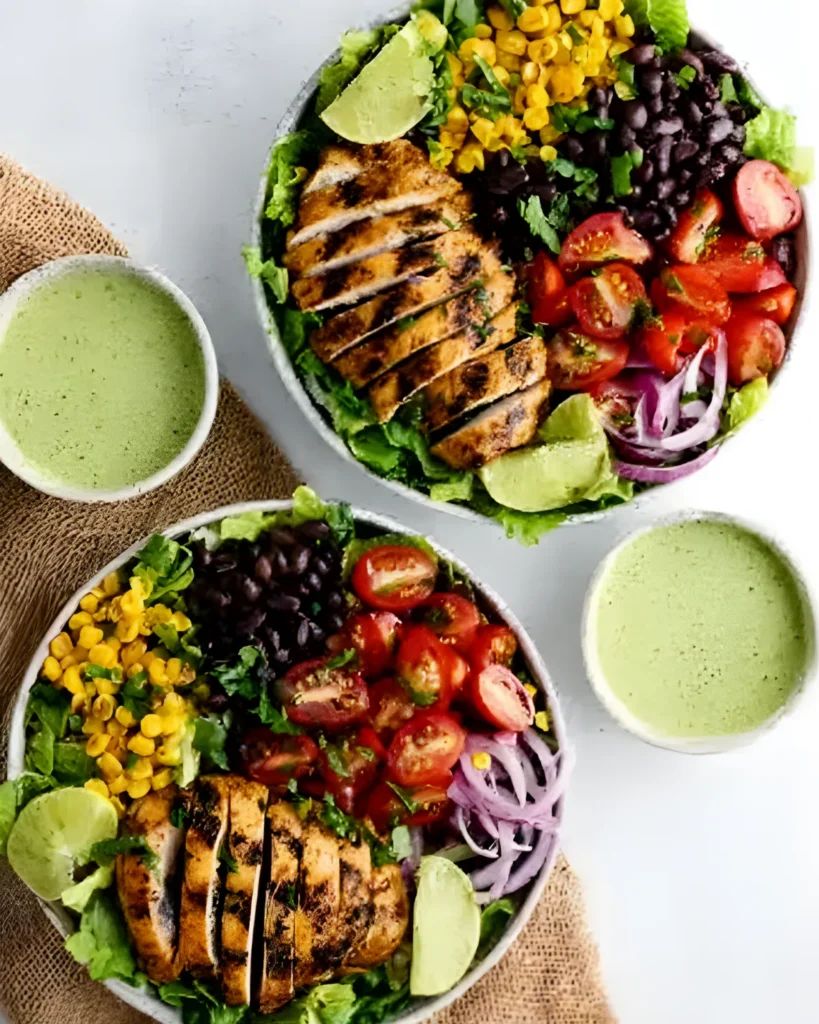 Two bowls of Southwest chicken salad with grilled chicken, black beans, corn, tomatoes, and cilantro dressing