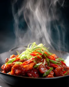 Crispy Chilli Beef served in a bowl with glossy spicy sauce, sliced red chilies, and fresh green onions.