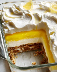 Creamy Lemon Lush in a glass dish with smooth lemon layers and piped whipped topping on top.