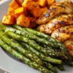 Air fryer asparagus recipes served with grilled chicken and roasted sweet potatoes on a dinner plate.